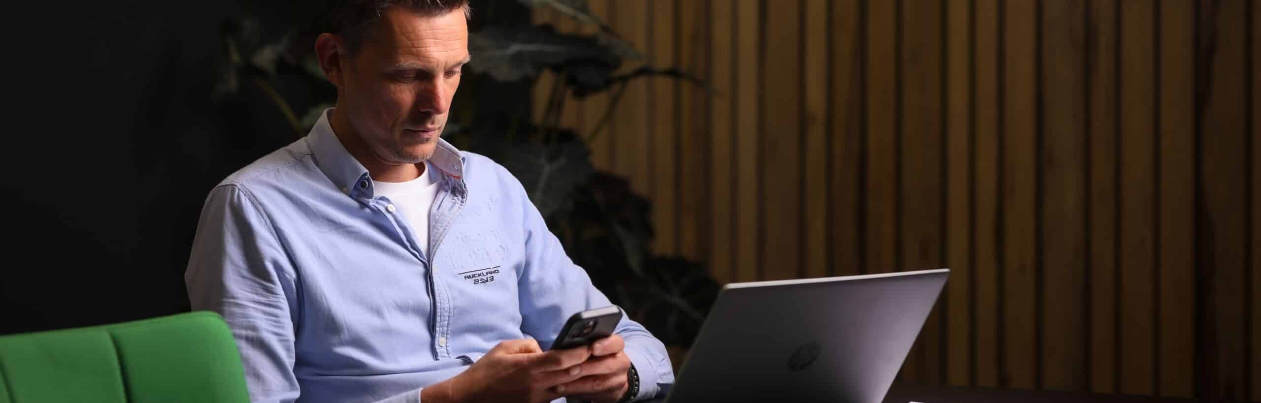 Kantoormedewerker werkt op beveiligde smartphone en laptop