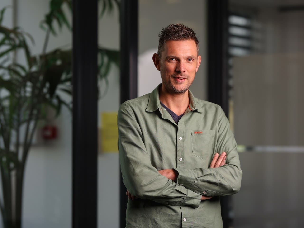 man met armen over elkaar kijkt in camera