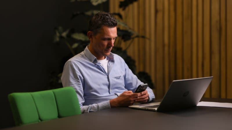 Man werkt op telefoon en laptop in de cloud