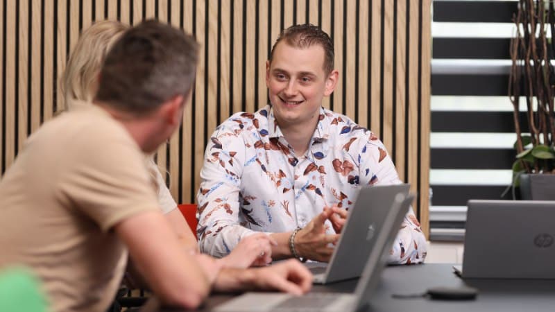 3 collega's werken op laptops in de cloud